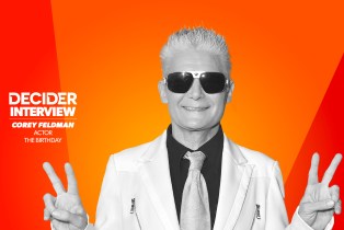 COREY FELDMAN in black and white on a bright orange background