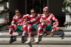 Three men and a boy sit on a front stoop dressed in red and white striped pajamas